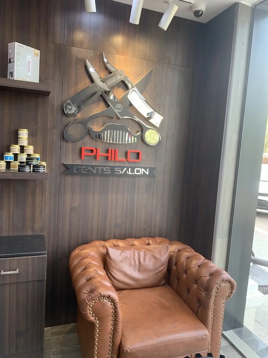 Leather chesterfield chair in front of the Philo Gents Salon logo wall